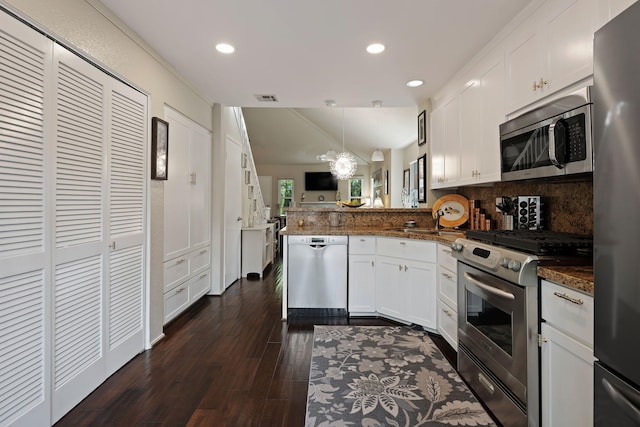 kitchen featuring white cabinets, stainless steel appliances, a peninsula, visible vents, and decorative backsplash