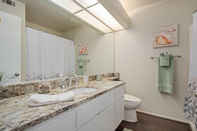 full bath with toilet, baseboards, visible vents, wood finished floors, and vanity