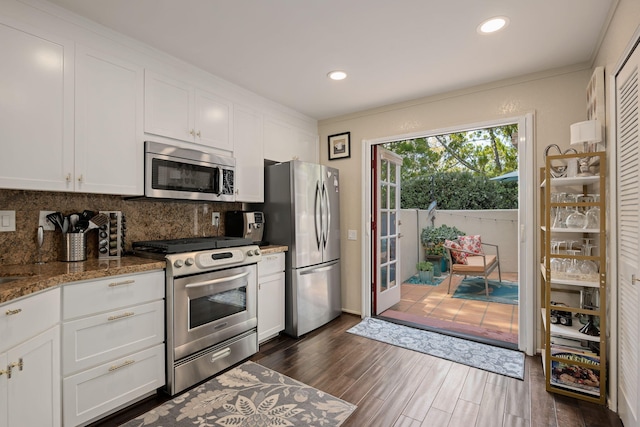 kitchen with recessed lighting, dark wood finished floors, tasteful backsplash, appliances with stainless steel finishes, and white cabinetry