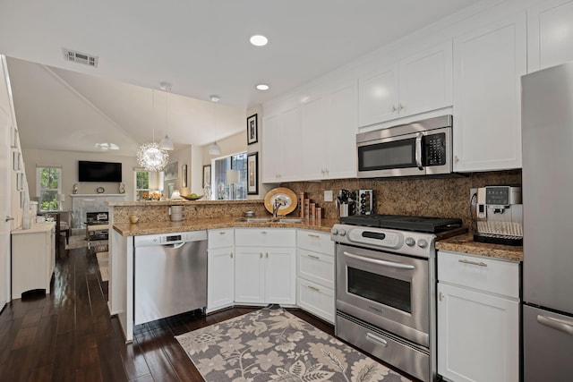 kitchen with open floor plan, dark wood finished floors, a peninsula, appliances with stainless steel finishes, and visible vents