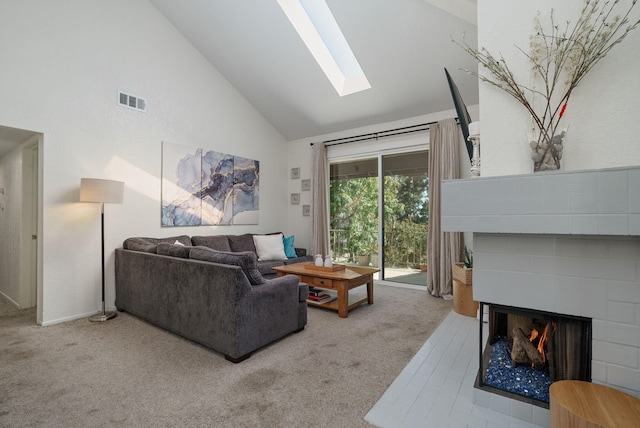 living area featuring carpet, visible vents, a multi sided fireplace, a skylight, and high vaulted ceiling