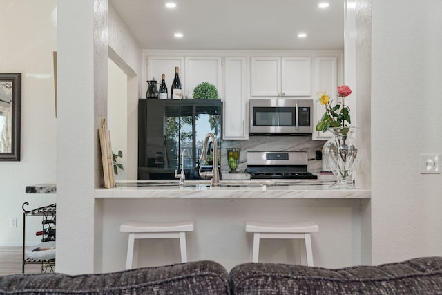 kitchen with white cabinets, a peninsula, appliances with stainless steel finishes, and recessed lighting