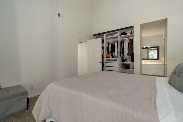 carpeted bedroom with baseboards, a towering ceiling, visible vents, and a closet
