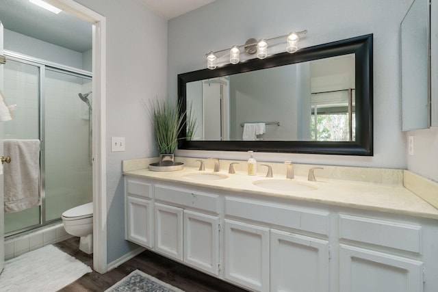 bathroom featuring a stall shower, a sink, double vanity, and toilet