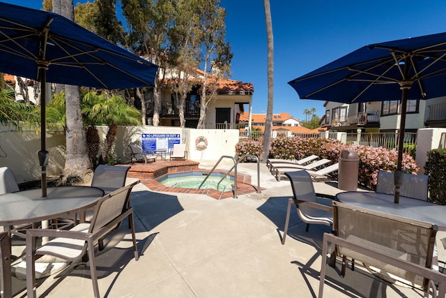 view of patio / terrace with fence, a community hot tub, and outdoor dining area