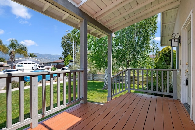 wooden deck featuring a porch, a residential view, a yard, and a mountain view