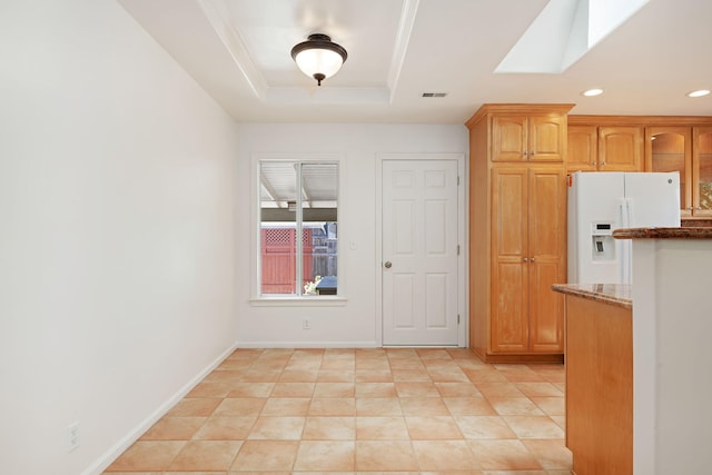 kitchen with dark stone countertops, white refrigerator with ice dispenser, baseboards, visible vents, and recessed lighting