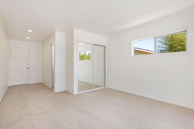 unfurnished bedroom with light colored carpet, baseboards, and a closet