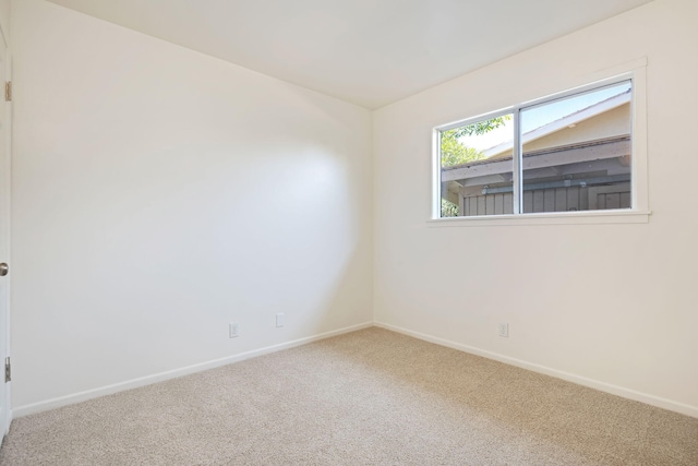 spare room featuring carpet and baseboards