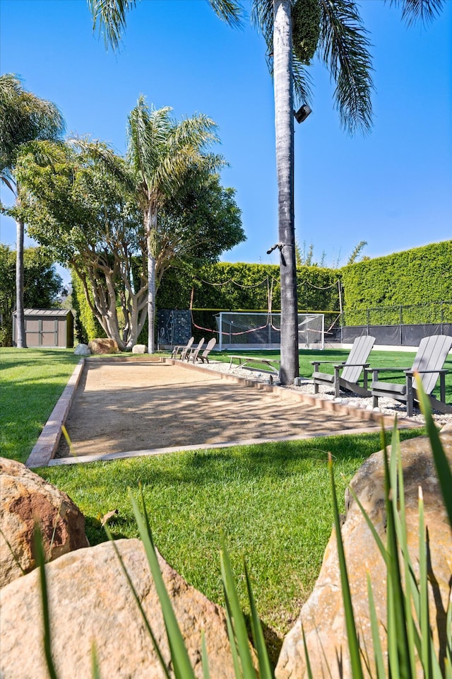 view of property's community featuring volleyball court, fence, and a lawn