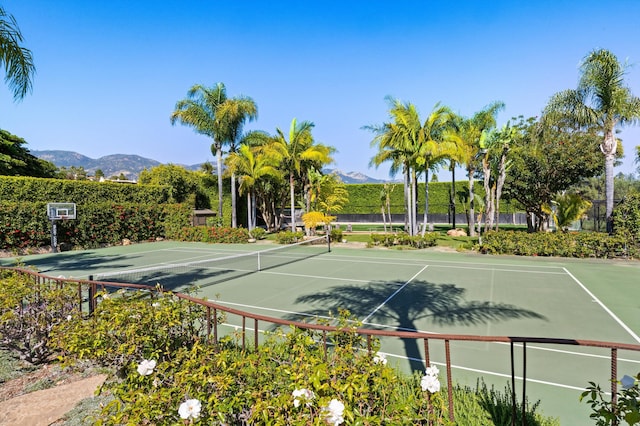 view of tennis court with fence and a mountain view