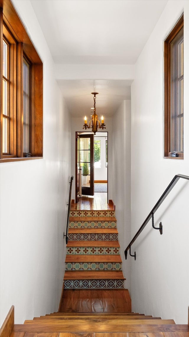 staircase with wood finished floors and a chandelier