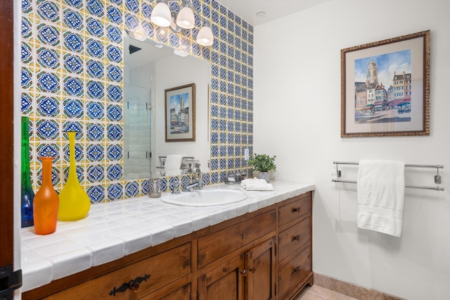 full bath featuring vanity, a tile shower, and visible vents