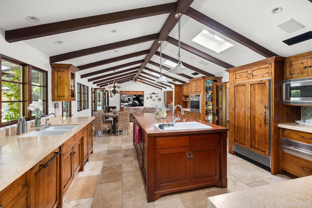 kitchen featuring stainless steel appliances, a warming drawer, a sink, and vaulted ceiling with skylight