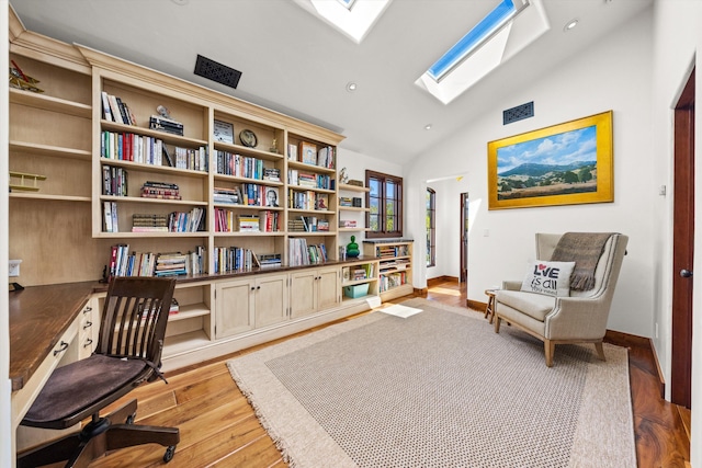 sitting room featuring vaulted ceiling with skylight, baseboards, light wood-style floors, and recessed lighting