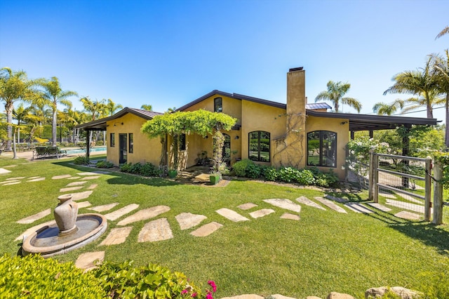 back of house featuring an outdoor pool, stucco siding, a chimney, metal roof, and a lawn