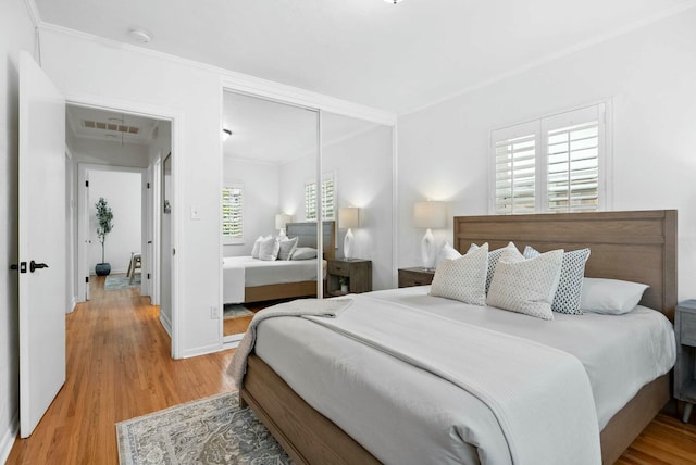 bedroom featuring visible vents, light wood-type flooring, a closet, crown molding, and baseboards