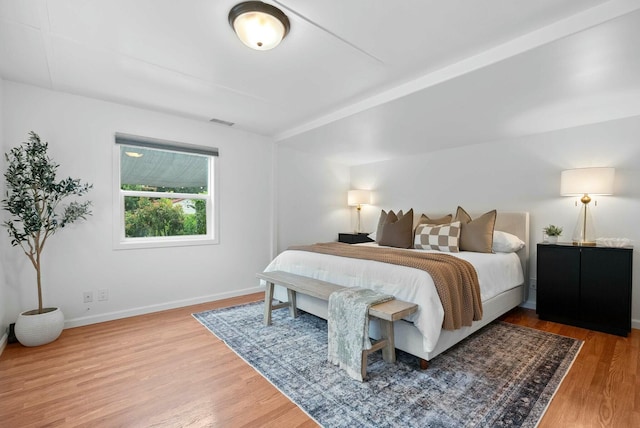 bedroom featuring baseboards, wood finished floors, and visible vents