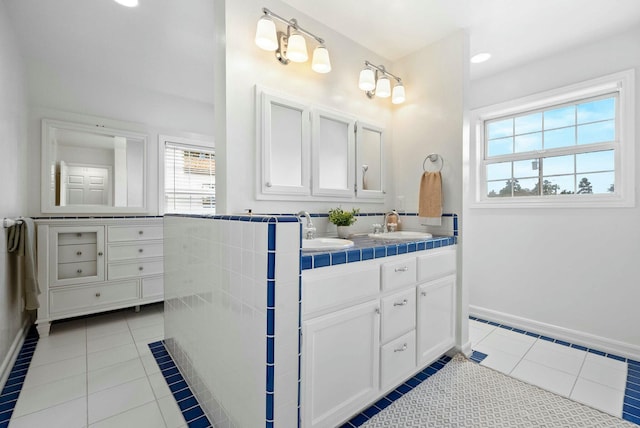 full bathroom with double vanity, tile patterned flooring, baseboards, and a sink