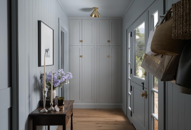 doorway to outside with light wood finished floors and a decorative wall