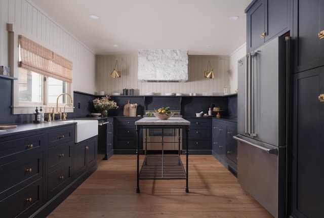 kitchen featuring dark countertops, light wood-type flooring, high end fridge, and a sink