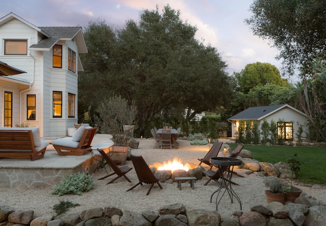 patio terrace at dusk featuring an outdoor living space with a fire pit