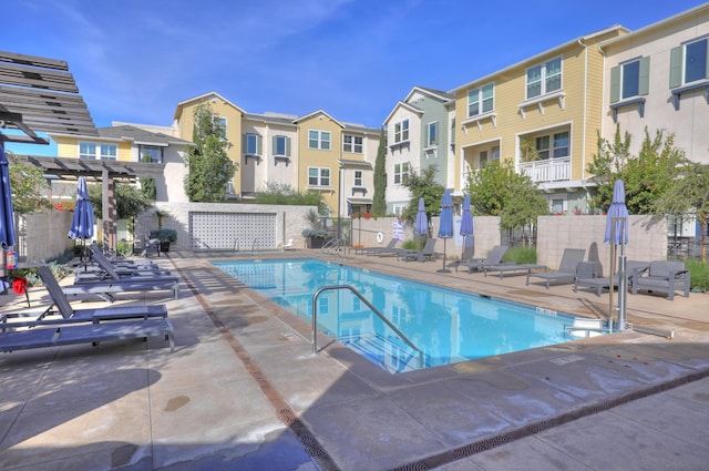 community pool with a pergola, fence, a residential view, and a patio