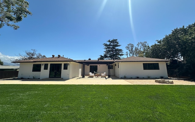 rear view of house with a lawn, a patio, and stucco siding