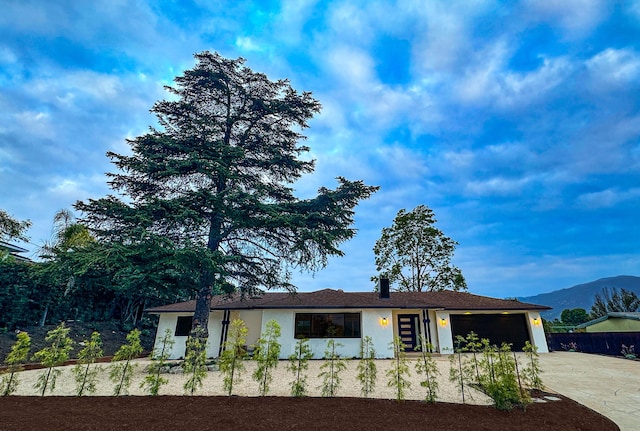 ranch-style home featuring fence, stucco siding, an attached garage, concrete driveway, and a mountain view