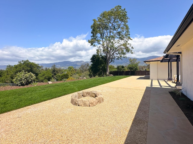 view of yard featuring a mountain view, fence, and a patio area