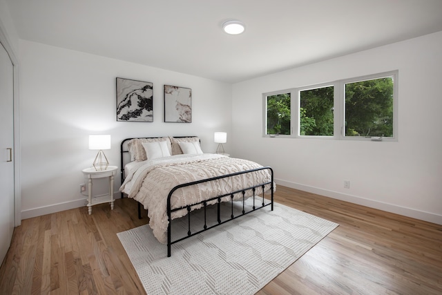 bedroom featuring light wood finished floors and baseboards