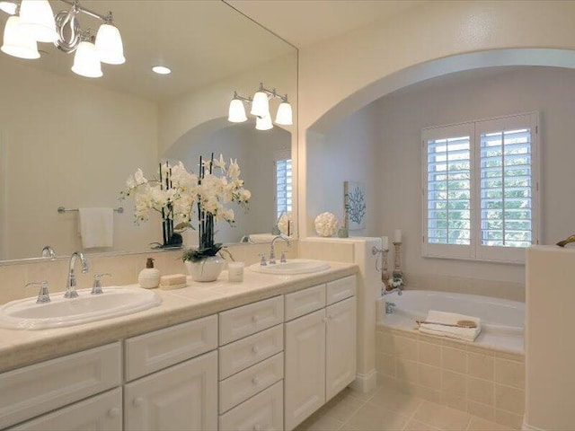 bathroom with a garden tub, tile patterned floors, a chandelier, and a sink