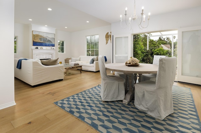 dining space featuring a tile fireplace, an inviting chandelier, light wood-style floors, and recessed lighting