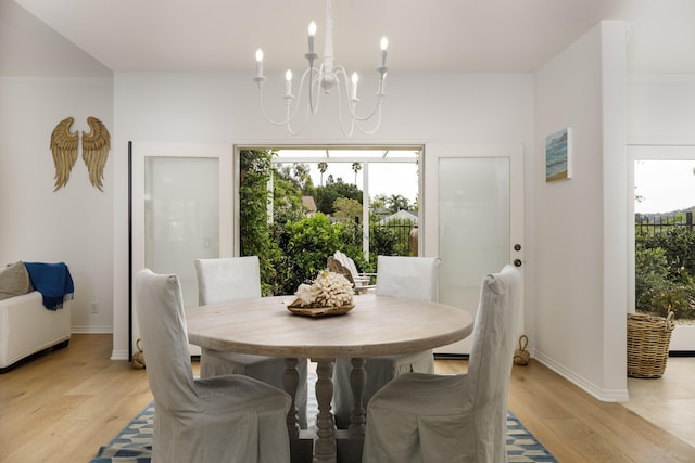 dining space with light wood-type flooring, baseboards, and an inviting chandelier