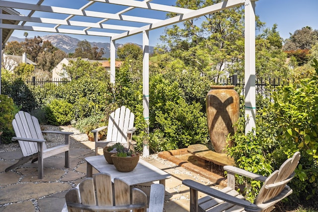 view of patio / terrace with fence, a pergola, and a mountain view