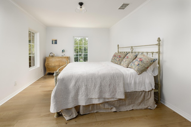 bedroom with ornamental molding, wood finished floors, and visible vents