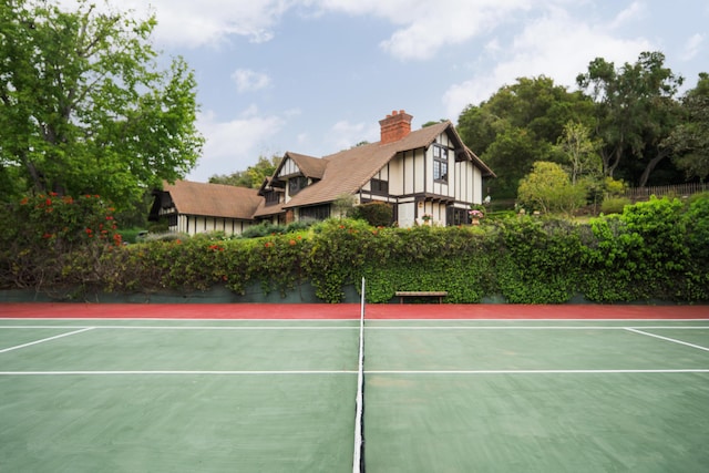 view of tennis court featuring community basketball court and fence
