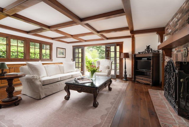 living area with wood-type flooring, coffered ceiling, a brick fireplace, and beamed ceiling