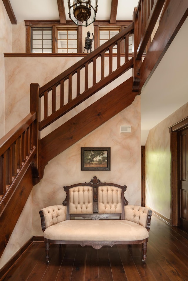 stairs with hardwood / wood-style floors, visible vents, beamed ceiling, baseboards, and a notable chandelier