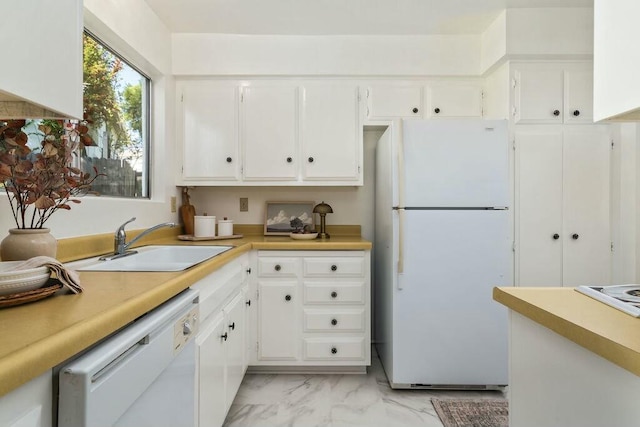 kitchen with white cabinets, light countertops, white appliances, and a sink