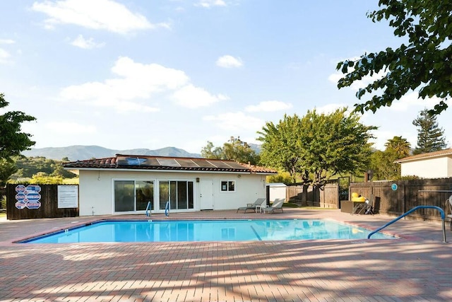 pool with a mountain view, fence, and a patio