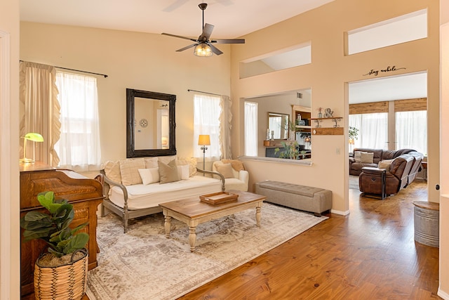 living area with wood finished floors, a ceiling fan, and a high ceiling