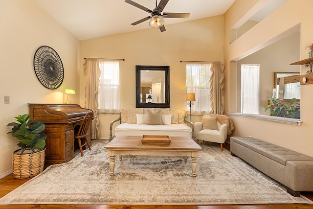 living area featuring wood finished floors, ceiling fan, vaulted ceiling, and baseboards