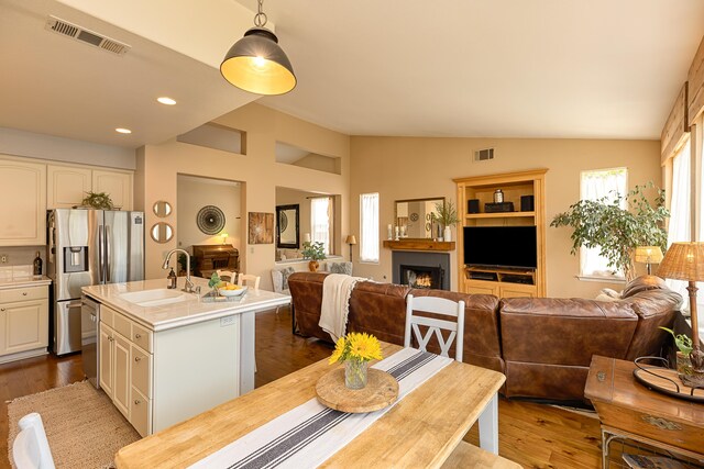 dining space featuring dark wood-style floors, visible vents, and vaulted ceiling