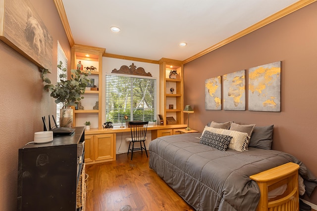 bedroom with ornamental molding, recessed lighting, built in desk, and wood finished floors