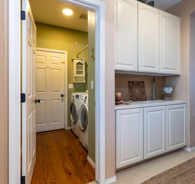 washroom with dark wood-style flooring, baseboards, cabinet space, and washing machine and dryer