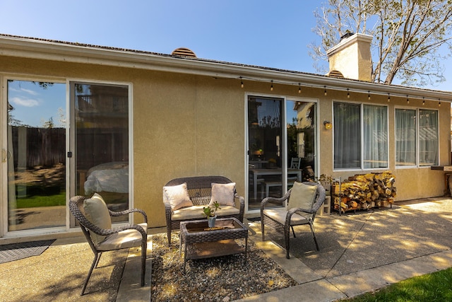rear view of property with a chimney, stucco siding, outdoor lounge area, and a patio area