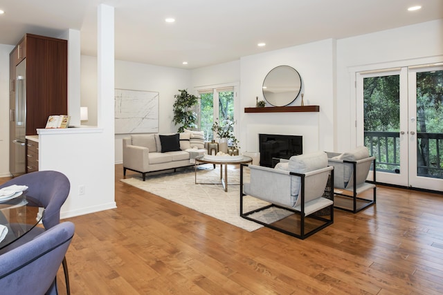 living area with recessed lighting, light wood finished floors, and a glass covered fireplace