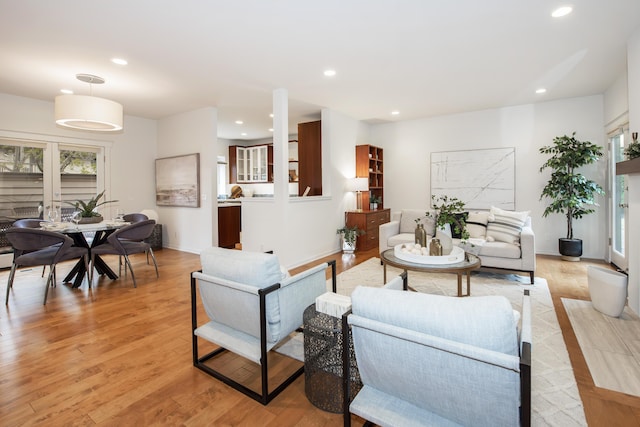 living area featuring baseboards, light wood-type flooring, and recessed lighting