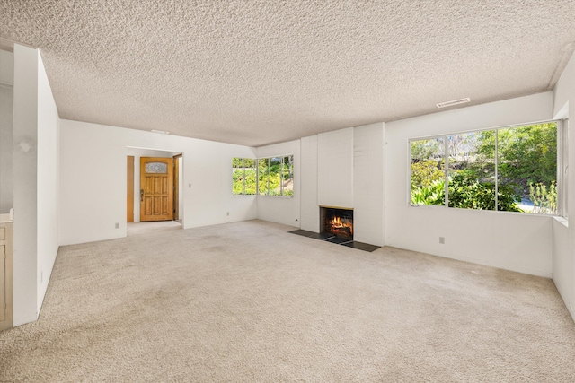 unfurnished living room featuring carpet floors, a textured ceiling, and a fireplace